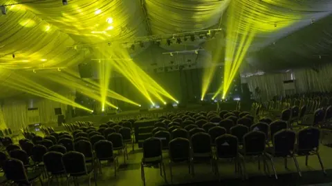 Yellow beams over a full auditorium